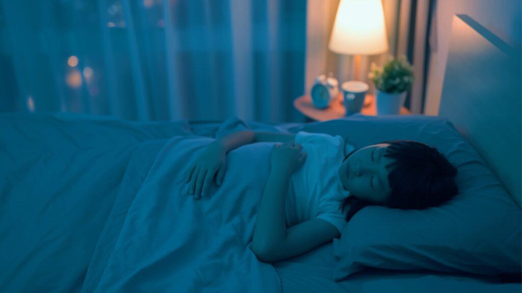 Asian girl asleep in her bed with a night light on