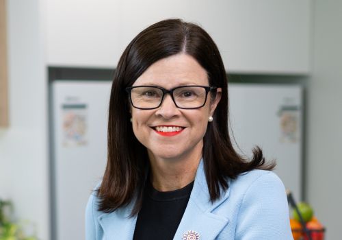 Dr Robyn Littlewood A portrait of a woman with long dark hair and dark rimmed reading glasses smiling at the camera.