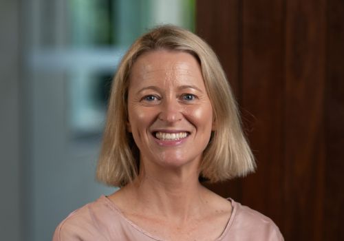 Fiona Nave A portrait of a woman with medium length blonde hair smiling at the camera.