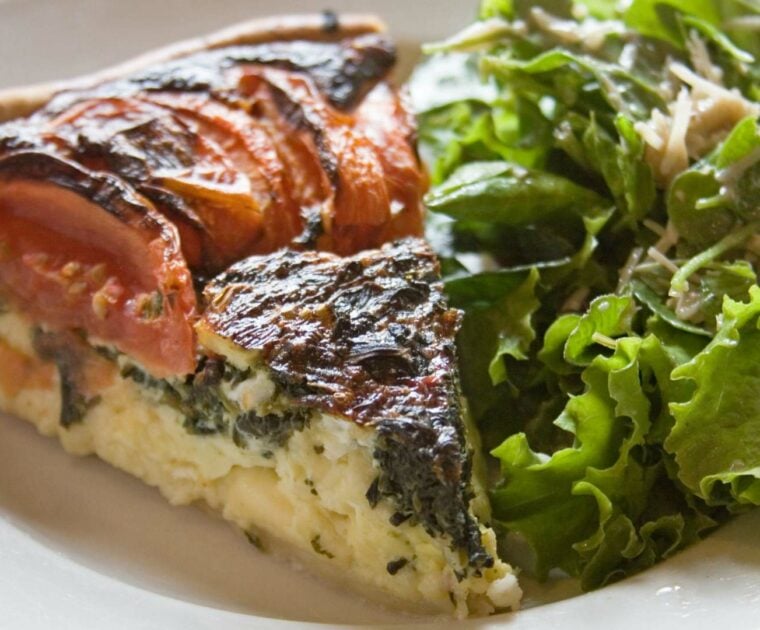 Slide of quiche and green salad on a plate