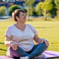 A woman sitting on a yoga mat in a park