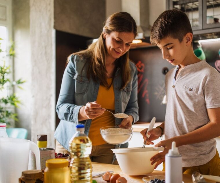 A woman teaching her son cooking skills in the kitchen
